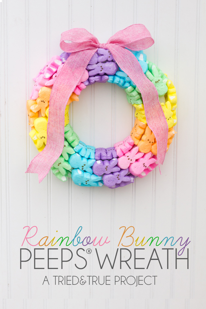 Easter wreath made of a rainbow of bunny peeps candies, with a pink bow on a white surface